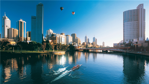 Rowers and hot air balloons over Melbourne skyline and Yarra River